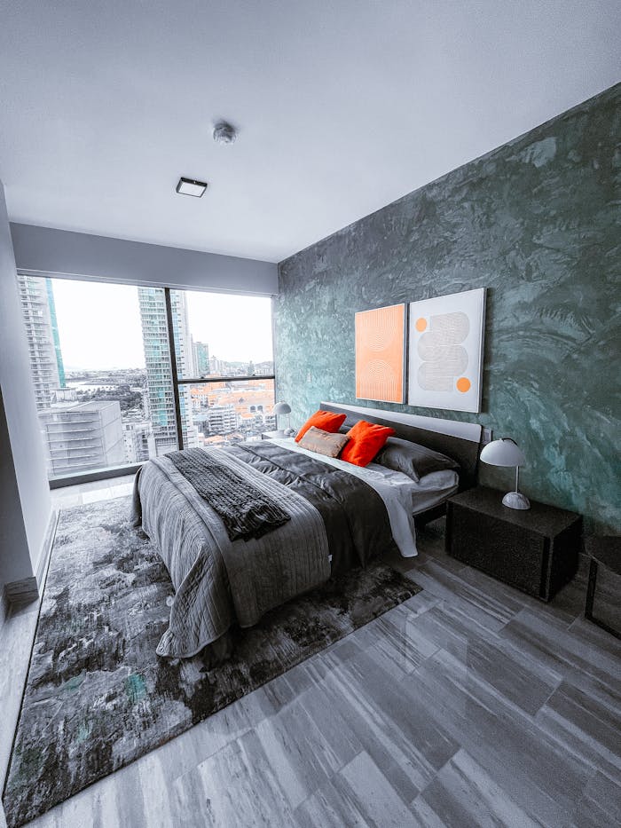 Sleek bedroom with green accent wall and city skyline view for modern living.